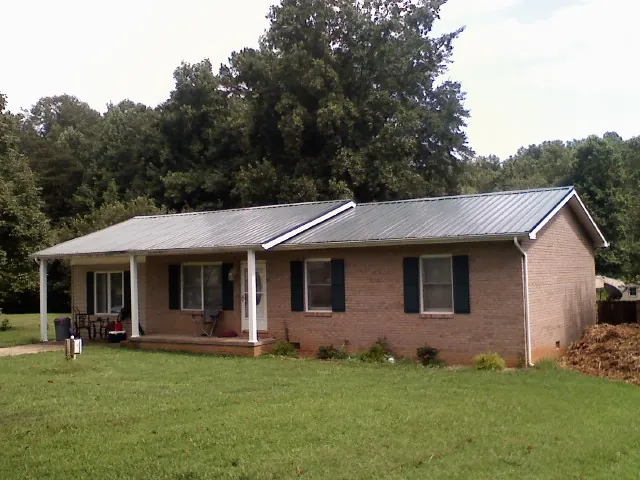 Gray metal roof on a brick ranch house with a side carport in Jetersville