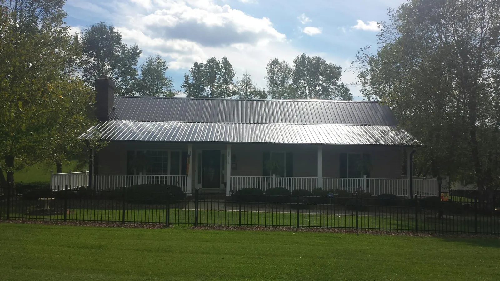 Gray metal roof on a brick ranch with a full width front porch — Gutter Guard Installation work by our crew in Jetersville