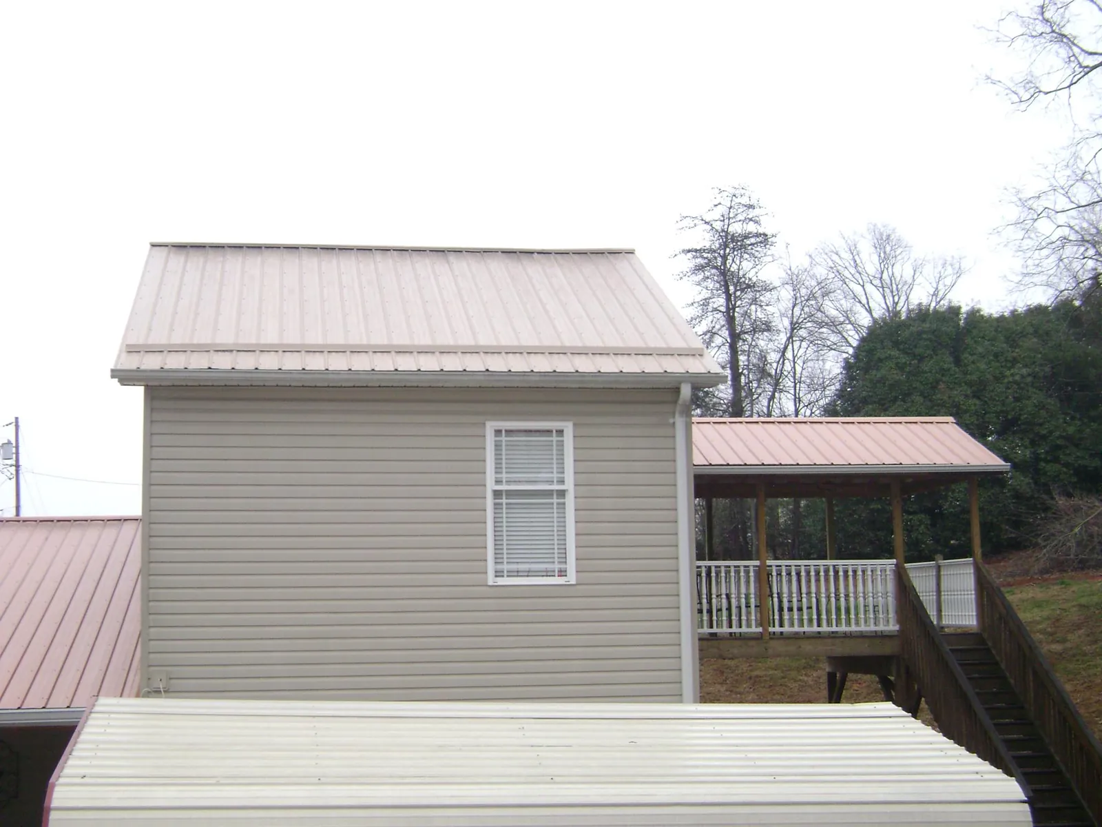 Tan metal roofs on a two story addition and attached porch, from a Roof Replacement job in Jetersville