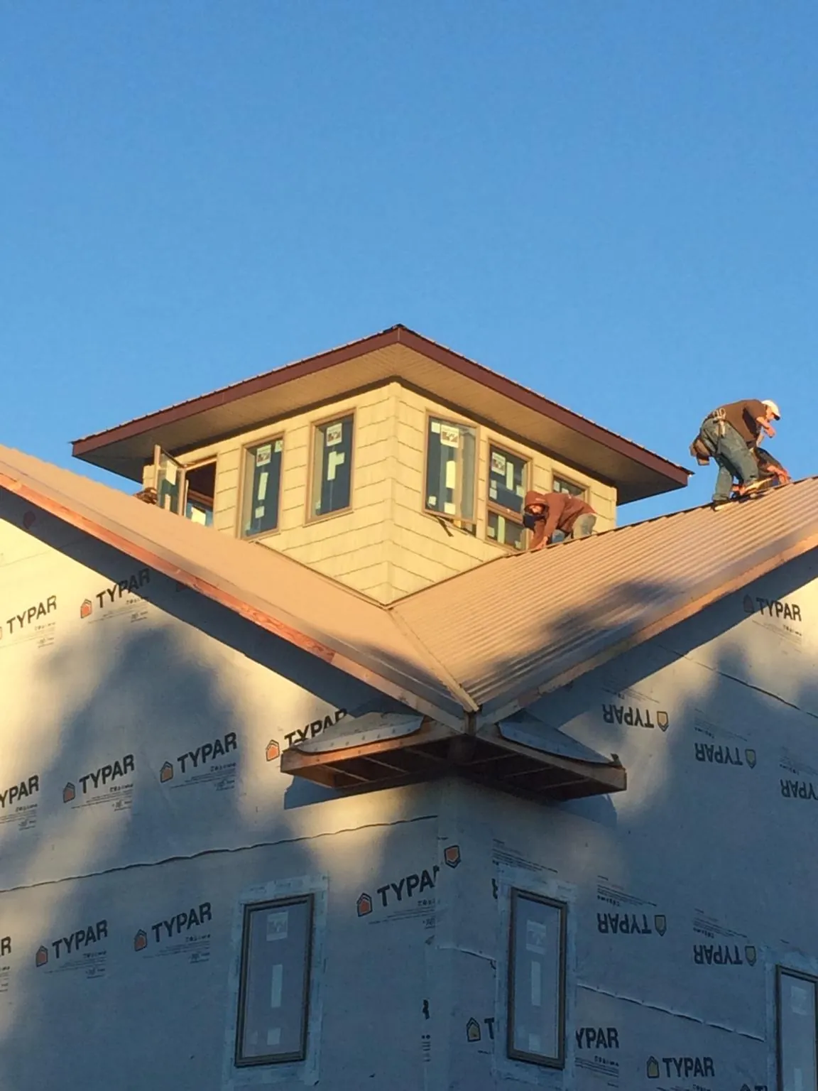Roofers working around a rooftop cupola on a new metal roof at sunset — Roof Waterproofing in Jetersville by Roofing Brothers